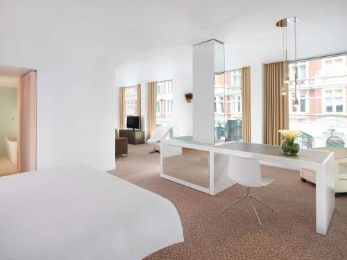 a bedroom with a white bed and a desk at St Martins Lane London in London