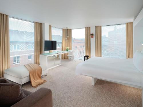 a white bedroom with a bed and a desk with a television at St Martins Lane London in London