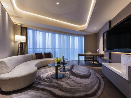 a living room with a couch and a tv at Grand Mercure Shanghai Lingang in Shanghai