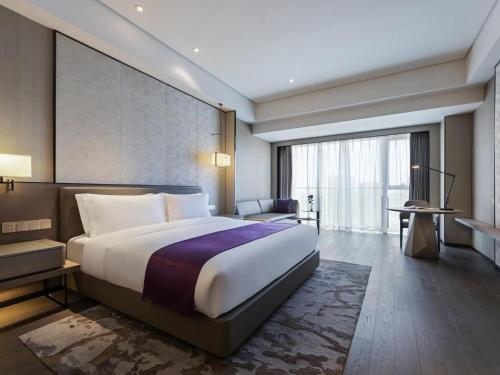 a bedroom with a large bed and a large window at Grand Mercure Shanghai Lingang in Shanghai