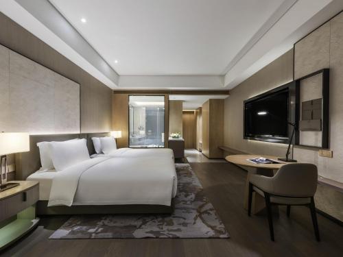 a bedroom with a large white bed and a desk at Grand Mercure Shanghai Lingang in Shanghai