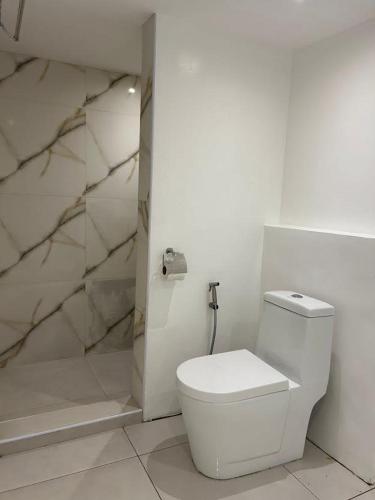 a white bathroom with a toilet and a shower at Anaya Beach Resort - Siargao in General Luna