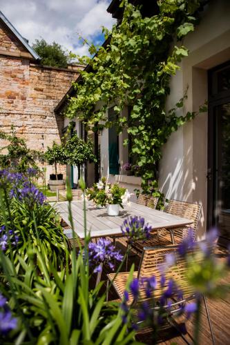 a patio with a table and chairs and purple flowers at Loblocher Hof in Neustadt an der Weinstraße