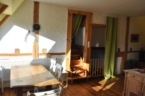 ein Esszimmer mit einem Tisch und einem grünen Vorhang in der Unterkunft Forsthaus Wilmeröderberg in Polle