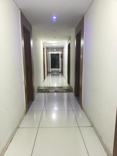 an empty corridor of a building with white floors and doors at Hotel Park in Jāmb