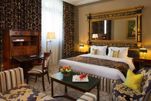 ジュネーヴにあるオテル ドゥ ラ シゴーニュの大きなベッドとデスクが備わるホテルルームです。