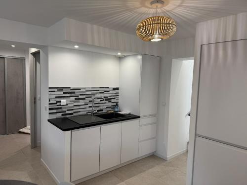 a white kitchen with a sink and a chandelier at La Petite Ancre in La Flotte