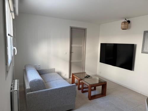 a living room with a couch and a flat screen tv at La Petite Ancre in La Flotte