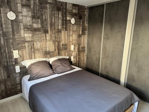 a bedroom with a bed with a wooden wall at La Petite Ancre in La Flotte