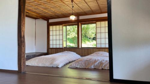 two beds in a room with two windows at 古民家かぐら in Tōno