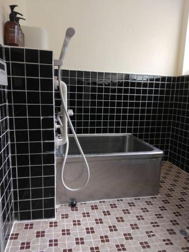 a bath tub in a bathroom with black tiles at 古民家かぐら in Tōno