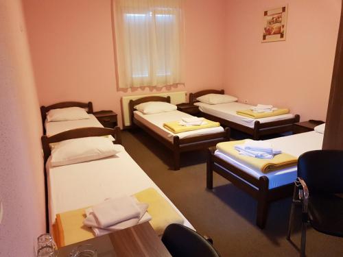 a room with four beds and a table and chairs at Hostel Kristal in Vinkovci