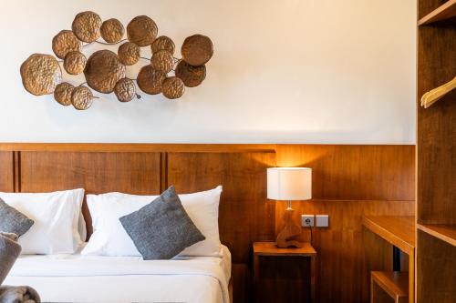 a bedroom with a bed with a wooden wall at Coconut Grove Villa by Betterplace in Ubud