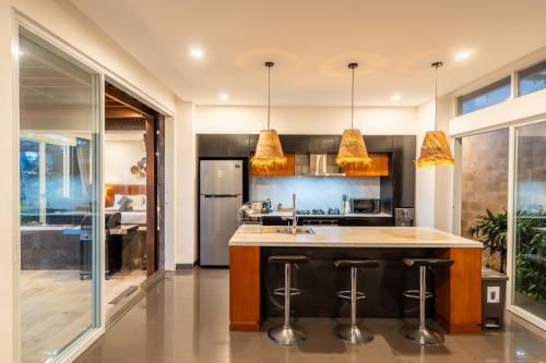 a kitchen with a large island with bar stools at Coconut Grove Villa by Betterplace in Ubud