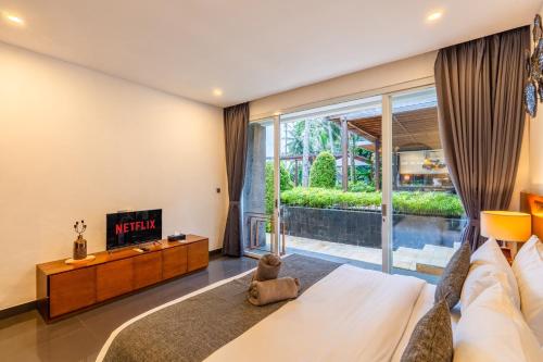 a bedroom with a large bed and a tv at Coconut Grove Villa by Betterplace in Ubud