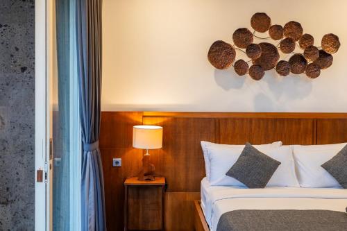 a bedroom with a bed and a lamp on a table at Coconut Grove Villa by Betterplace in Ubud