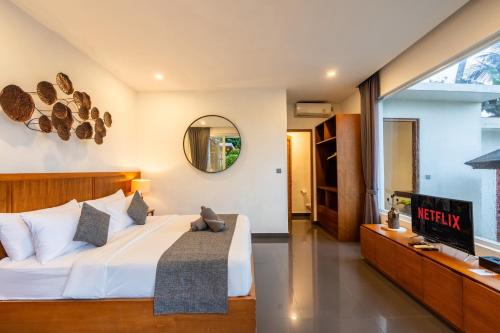 a bedroom with a large bed and a mirror at Coconut Grove Villa by Betterplace in Ubud