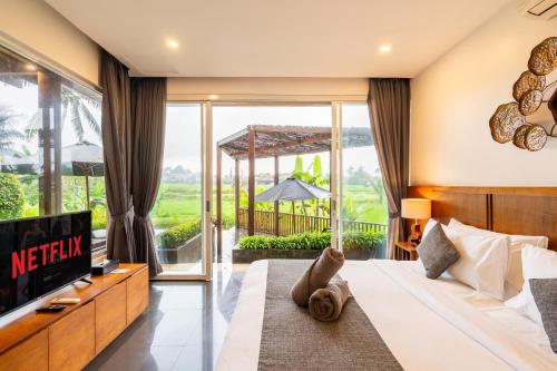 a bedroom with a bed and a tv and a window at Coconut Grove Villa by Betterplace in Ubud