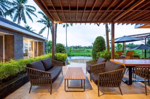 a patio with chairs and a table with a view of a river at Coconut Grove Villa by Betterplace in Ubud