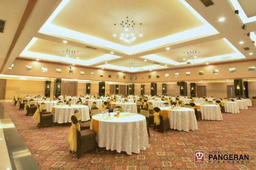 a banquet hall with white tables and people sitting at them at Hotel Pangeran in Pekanbaru