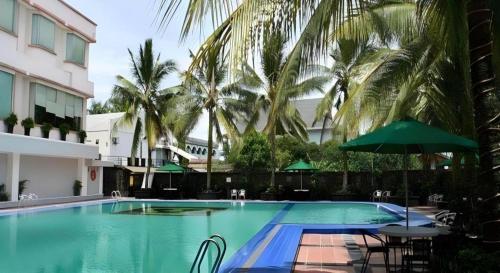 a large swimming pool with chairs and an umbrella at Hotel Pangeran in Pekanbaru