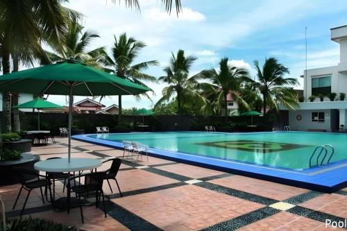 a swimming pool with tables and chairs and an umbrella at Hotel Pangeran in Pekanbaru