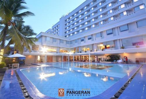 a large swimming pool in front of a hotel at Hotel Pangeran in Pekanbaru