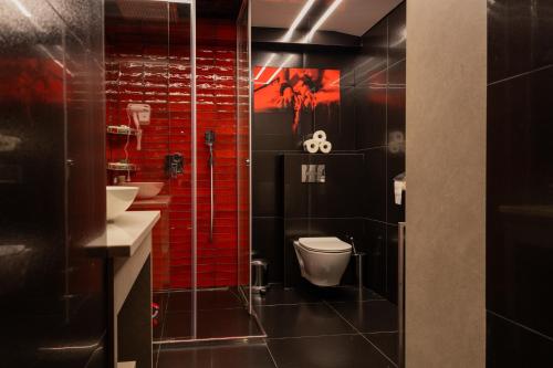 a bathroom with a toilet and a sink and red tiles at Apartament Grey in Tuchola