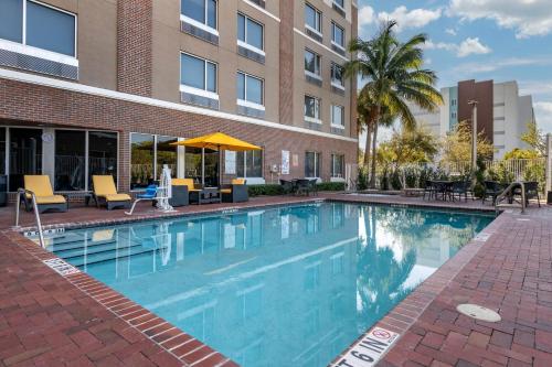 a swimming pool with chairs and a building at Cambria Hotel Ft Lauderdale, Airport South & Cruise Port in Dania Beach