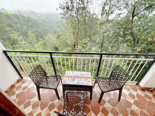 a balcony with two chairs and a table and a view at Nature View Home Stay in Vagamon