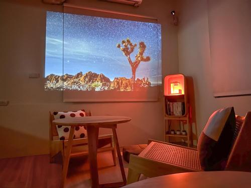 a room with a table and a screen with a tree on the wall at 青日所 Midoriya in Tainan