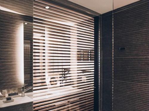 a bathroom with a large window with wooden blinds at SLS Buenos Aires Puerto Madero in Buenos Aires
