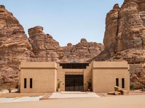 a building in front of a rocky mountain at Shaden Resort in AlUla