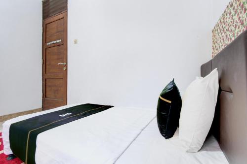 a bedroom with a bed with white sheets and pillows at SPOT ON Podomoro Homestay in Yogyakarta