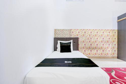 a bedroom with a white bed with a black pillow at SPOT ON Podomoro Homestay in Yogyakarta