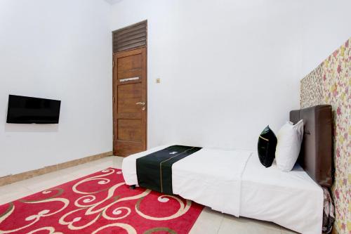 a bedroom with a bed and a tv on a wall at SPOT ON Podomoro Homestay in Yogyakarta