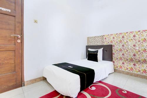 a bedroom with a large white bed and a wooden door at SPOT ON Podomoro Homestay in Yogyakarta