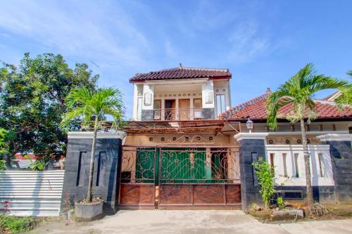 a house with a green gate and palm trees at SPOT ON Podomoro Homestay in Yogyakarta