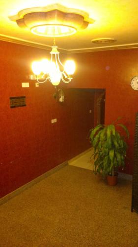Cette chambre est dotée d'un plafond avec un lustre et une plante. dans l'établissement شقق ضيافة خاصة, à Yanbu