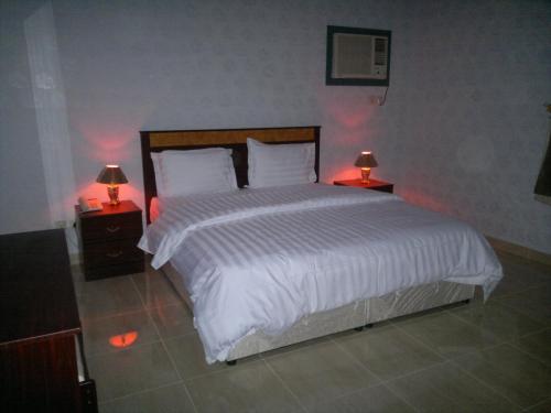 1 dormitorio con 1 cama blanca grande y 2 lámparas en شقق ضيافة خاصة, en Yanbu