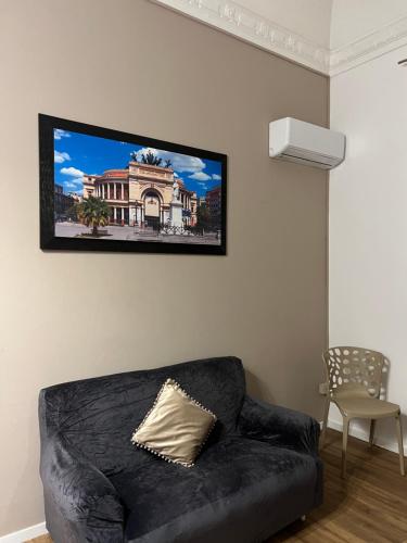 a black couch in a living room with a tv on the wall at Le suite di Alba in Palermo