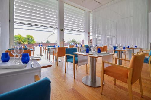 a dining room with tables and chairs and windows at Hotel Hiberus in Zaragoza