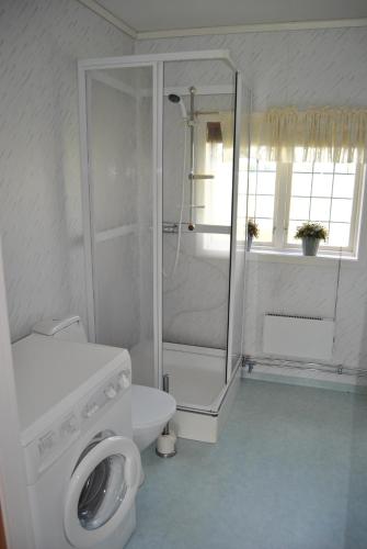 a white bathroom with a shower and a toilet at Orsastuguthyrning-Hansjö in Orsa