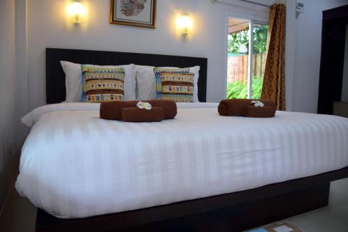 a large white bed with two brown pillows on it at Baan Longhaad in Ko Lanta