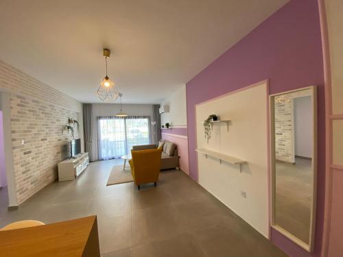 a living room with purple walls and a yellow chair at Garden View Two Bedroom Apartment in Caesar Resort & SPA, Long Beach in Perivolia tou Trikomou