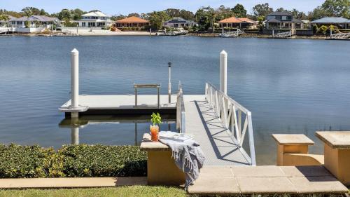 a dock on a lake with houses in the background at Point Paradiso - Your Ultimate Family Waterfront Escape - Holiday Yamba in Yamba