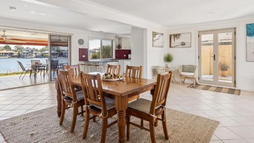 a kitchen and dining room with a wooden table and chairs at Point Paradiso - Your Ultimate Family Waterfront Escape - Holiday Yamba in Yamba