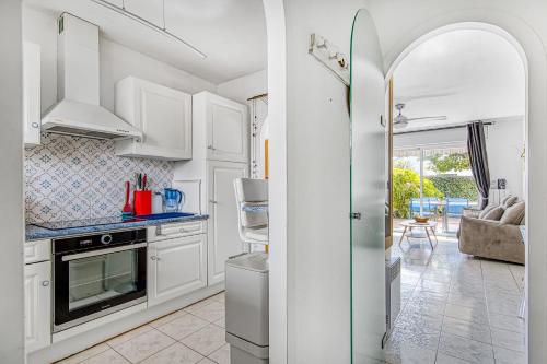 a kitchen with white cabinets and a view of a living room at Appartement bord de bassin in Andernos-les-Bains