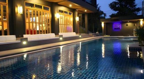 a swimming pool in front of a house at night at Villa Gris Pranburi in Pran Buri