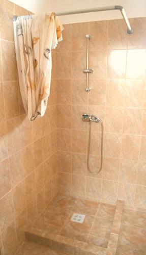 a bathroom with a shower with a towel hanging on the wall at Casute de Vacanta - Complex Ben in Ocna Sibiului